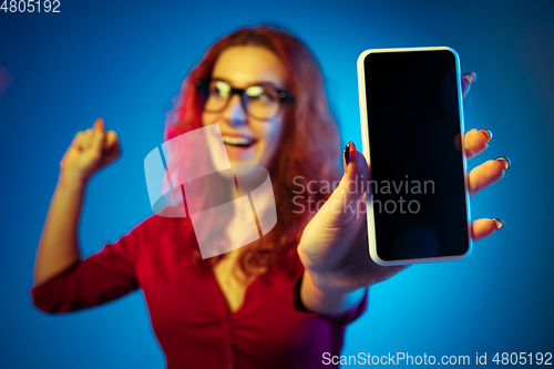 Image of Caucasian woman\'s portrait isolated on blue studio background in neon light