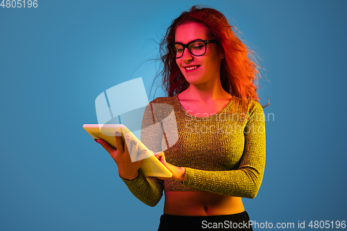 Image of Caucasian woman\'s portrait isolated on blue studio background in neon light