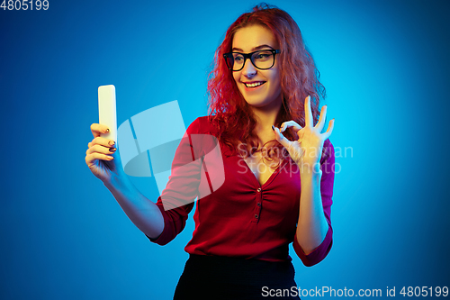 Image of Caucasian woman\'s portrait isolated on blue studio background in neon light
