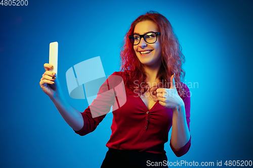 Image of Caucasian woman\'s portrait isolated on blue studio background in neon light