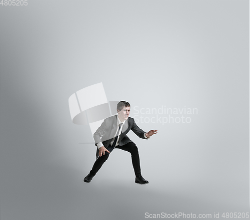 Image of Caucasian man in office clothes training isolated on grey studio background