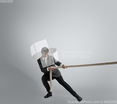 Image of Caucasian man in office clothes training isolated on grey studio background