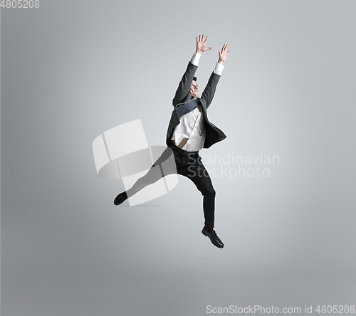 Image of Caucasian man in office clothes training isolated on grey studio background