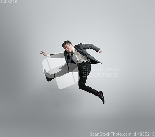 Image of Caucasian man in office clothes running isolated on grey studio background
