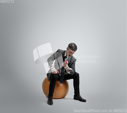 Image of Caucasian man in office clothes training isolated on grey studio background