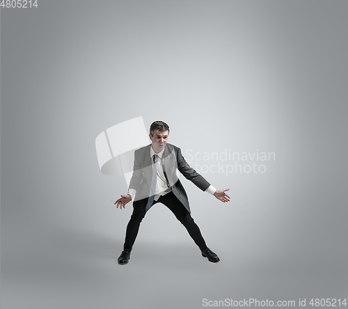 Image of Caucasian man in office clothes training isolated on grey studio background