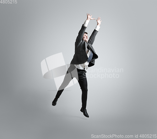 Image of Caucasian man in office clothes training isolated on grey studio background