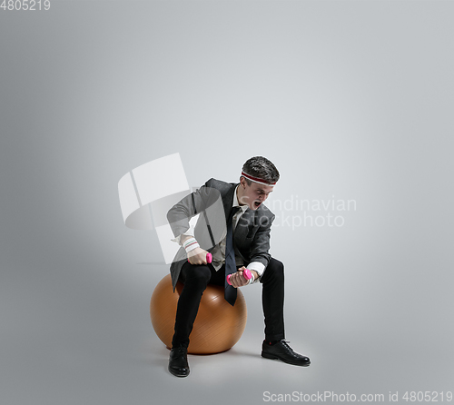 Image of Caucasian man in office clothes training isolated on grey studio background