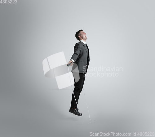 Image of Caucasian man in office clothes training isolated on grey studio background