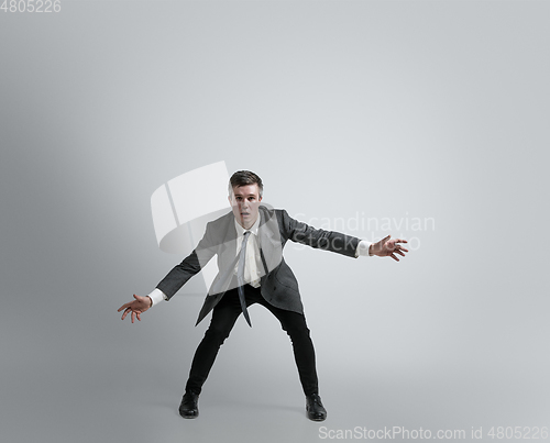 Image of Caucasian man in office clothes training isolated on grey studio background