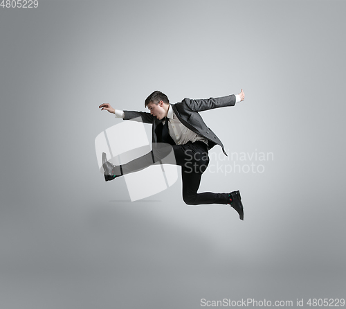 Image of Caucasian man in office clothes running isolated on grey studio background