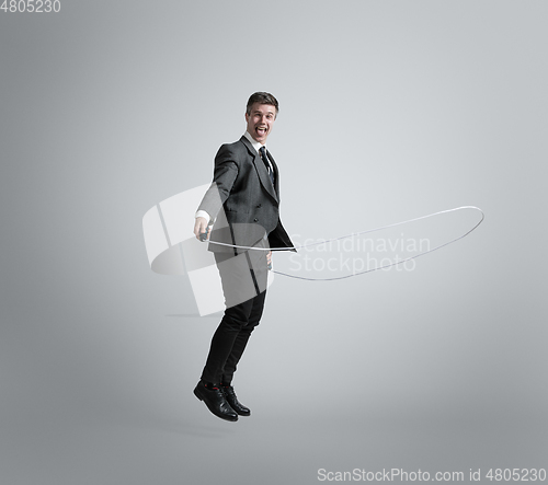 Image of Caucasian man in office clothes training isolated on grey studio background