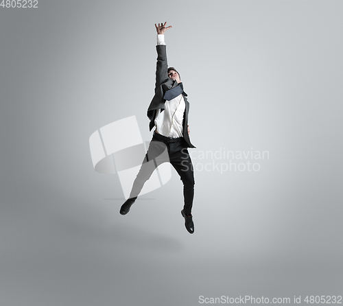 Image of Caucasian man in office clothes training isolated on grey studio background