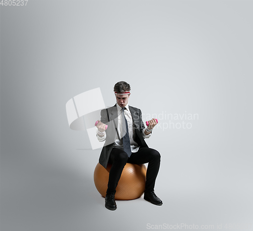 Image of Caucasian man in office clothes training isolated on grey studio background