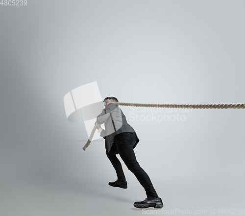 Image of Caucasian man in office clothes training isolated on grey studio background