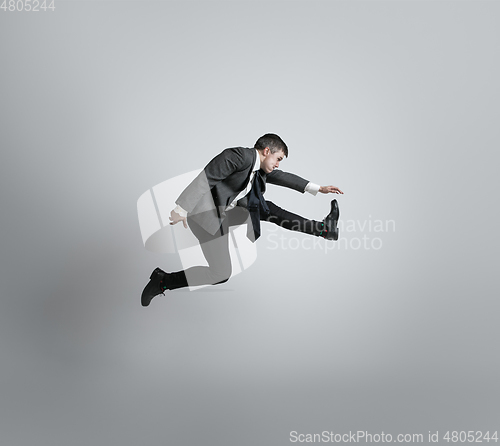 Image of Caucasian man in office clothes running isolated on grey studio background