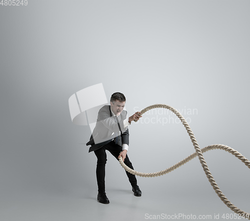 Image of Caucasian man in office clothes training isolated on grey studio background