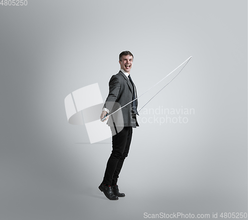 Image of Caucasian man in office clothes training isolated on grey studio background