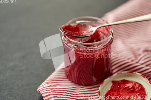 Image of mason jar with raspberry jam and spoon on towel