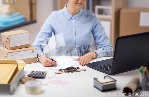 Image of woman with laptop and clipboard at post office