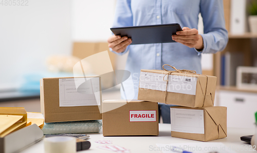 Image of woman with tablet pc and parcels at post office