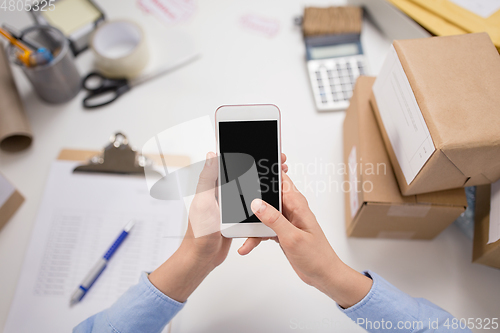 Image of hands with smartphone and parcels at post office