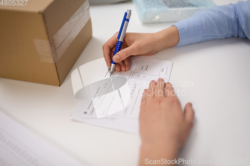 Image of close up of woman filling postal form at office