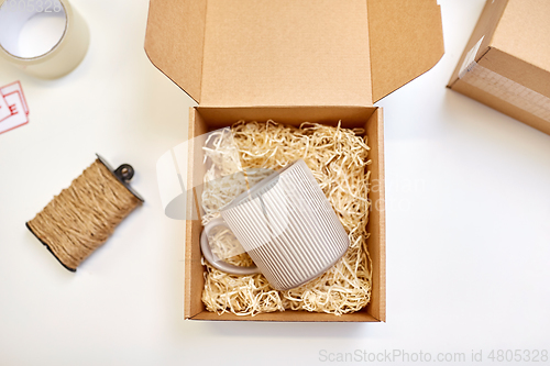 Image of parcel with straw filler and mug at post office