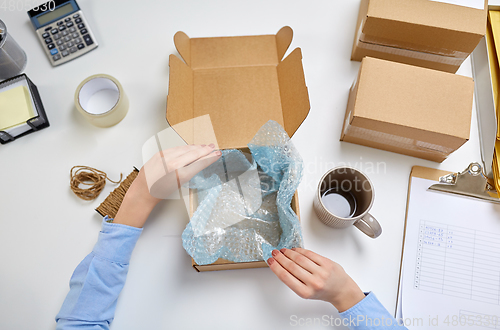 Image of hands packing mug to parcel box at post office