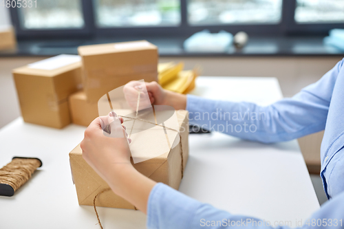 Image of woman packing parcel and tying rope at post office