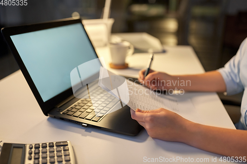 Image of businesswoman with papers working at night office