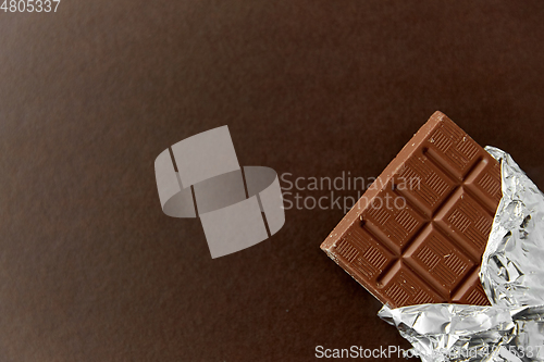 Image of chocolate bar in foil wrapper on brown background