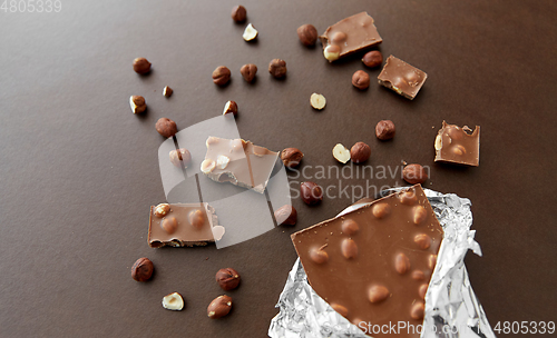 Image of milk chocolate bar with hazelnuts in foil wrapper