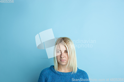 Image of Portrait of young caucasian woman looks happy, dreamful on blue background