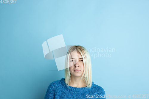 Image of Portrait of young caucasian woman looks happy, dreamful on blue background