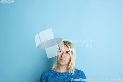 Image of Portrait of young caucasian woman looks happy, dreamful on blue background
