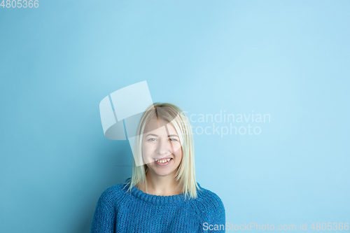 Image of Portrait of young caucasian woman looks happy, dreamful on blue background