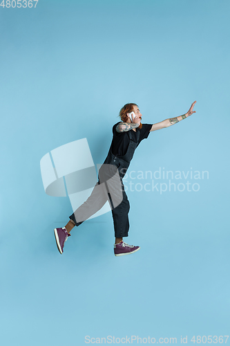 Image of Portrait of young caucasian man looks happy, jumping on blue background