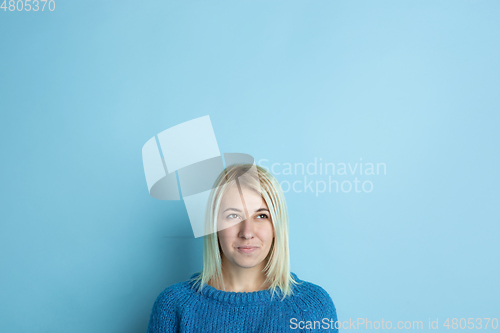 Image of Portrait of young caucasian woman looks happy, dreamful on blue background