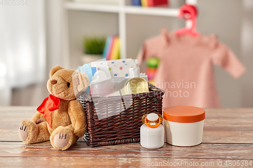 Image of baby things in basket and teddy bear toy on table
