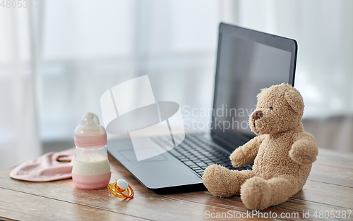 Image of baby milk formula, laptop, soother and teddy bear