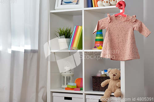 Image of kid's room interior with bookcase and dress