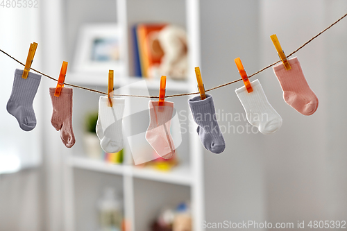 Image of little socks for baby girl on clothesline at home