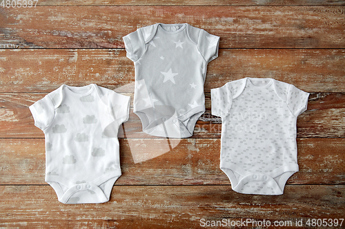 Image of baby clothes set of bodysuits on wooden table