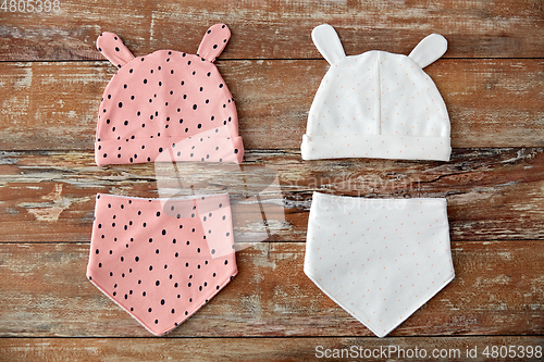 Image of baby hats with ears and bibs on wooden table