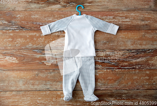 Image of baby clothes set with hanger on wooden table