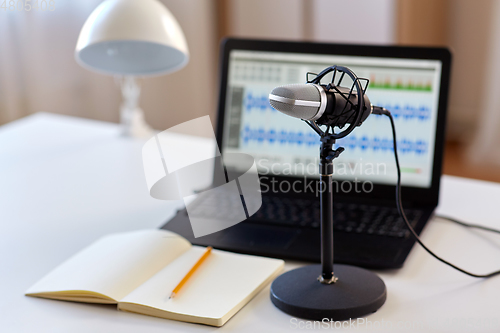 Image of microphone, laptop and notebook on table