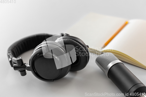 Image of headphones, microphone and notebook with pencil