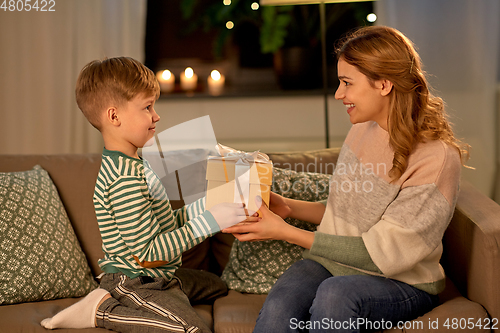 Image of little son giving present to mother at home