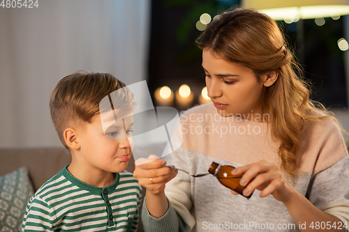 Image of mother giving medication or cough syrup to ill son